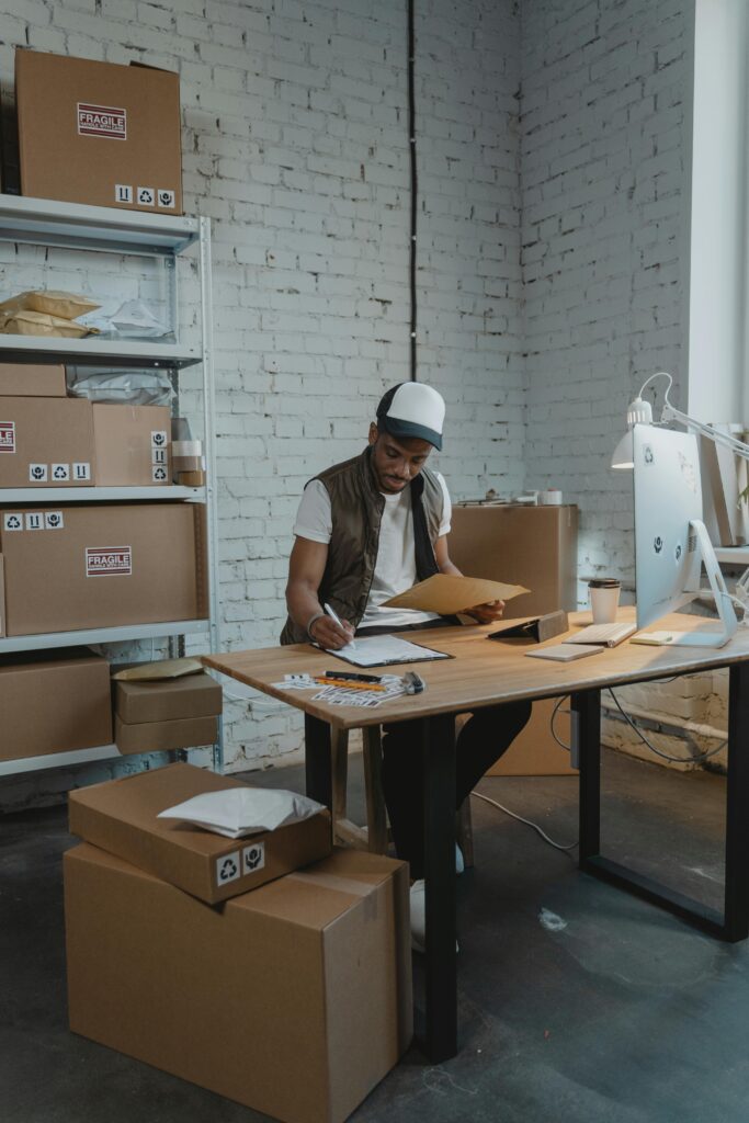 A warehouse employee processing orders amidst parcels and cardboard boxes.