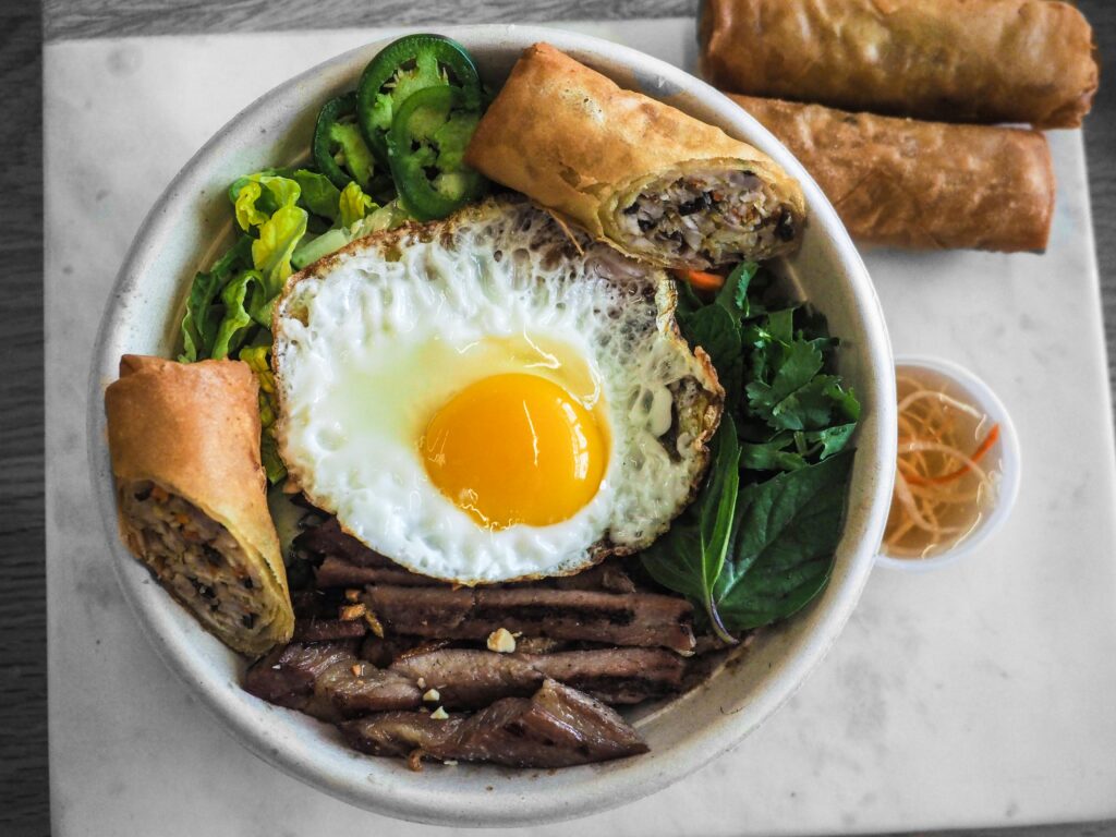 A vibrant Vietnamese pho bowl with egg and spring rolls, perfect for a healthy meal.