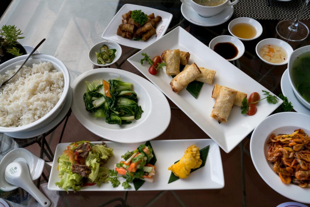 A colorful spread of Vietnamese dishes including rice, vegetables, and spring rolls.